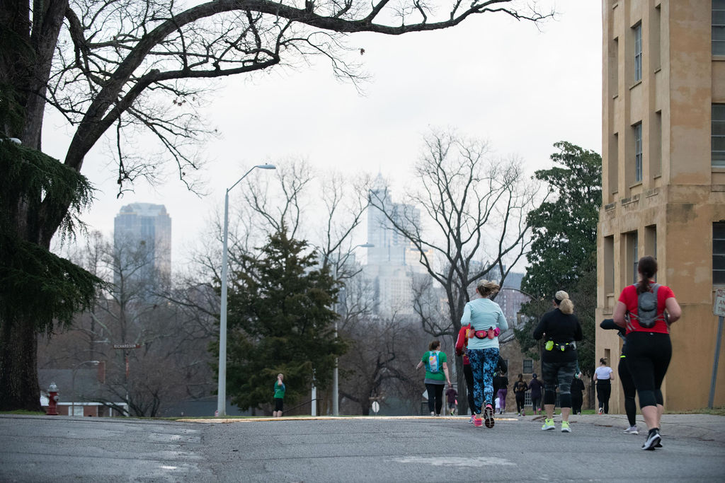 runners from behind with city skyline in background