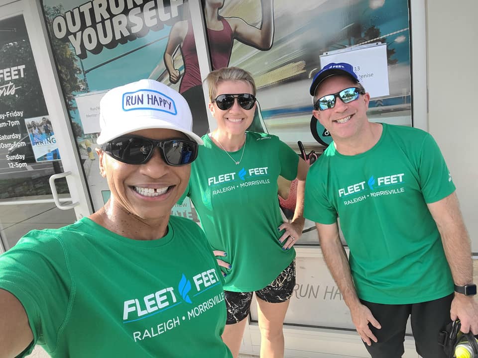 three people wearing matching green Fleet Feet Running Club t-shirts