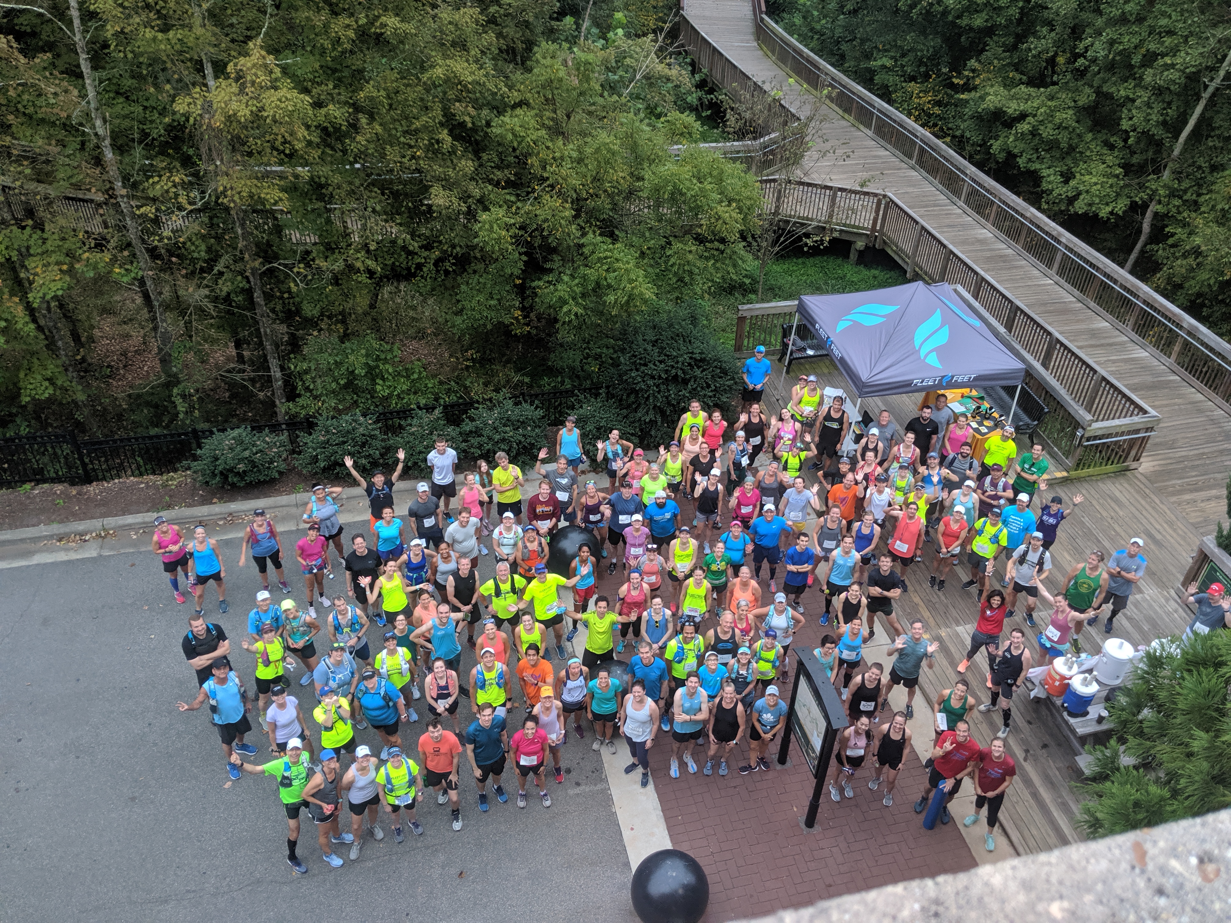 looking down from a parking garage on a large group of runners with a fleet feet tent