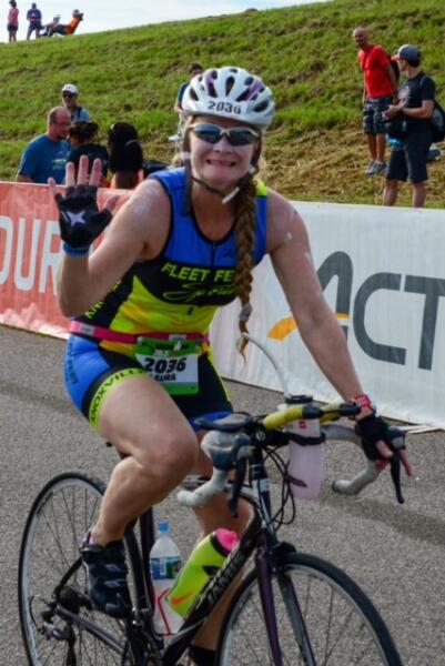 Laura biking at IRONMAN 70.3 Augusta and waving at the camera