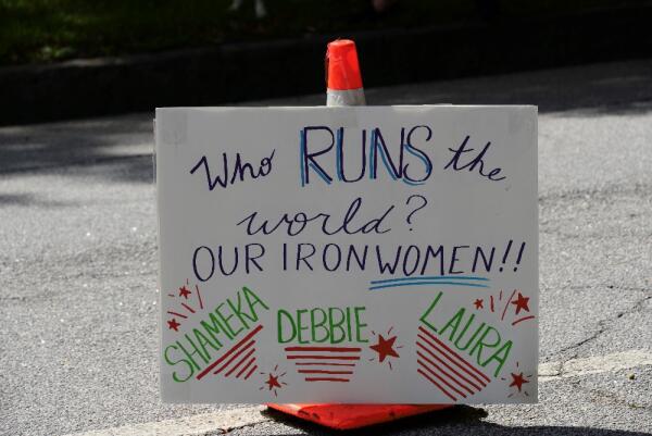 "Who runs the world? Our Ironwomen!" sign with athlete names - Shameka, Debbie, Laura