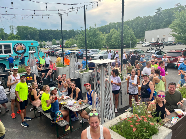 people sitting on picnic tables with food truck in the background