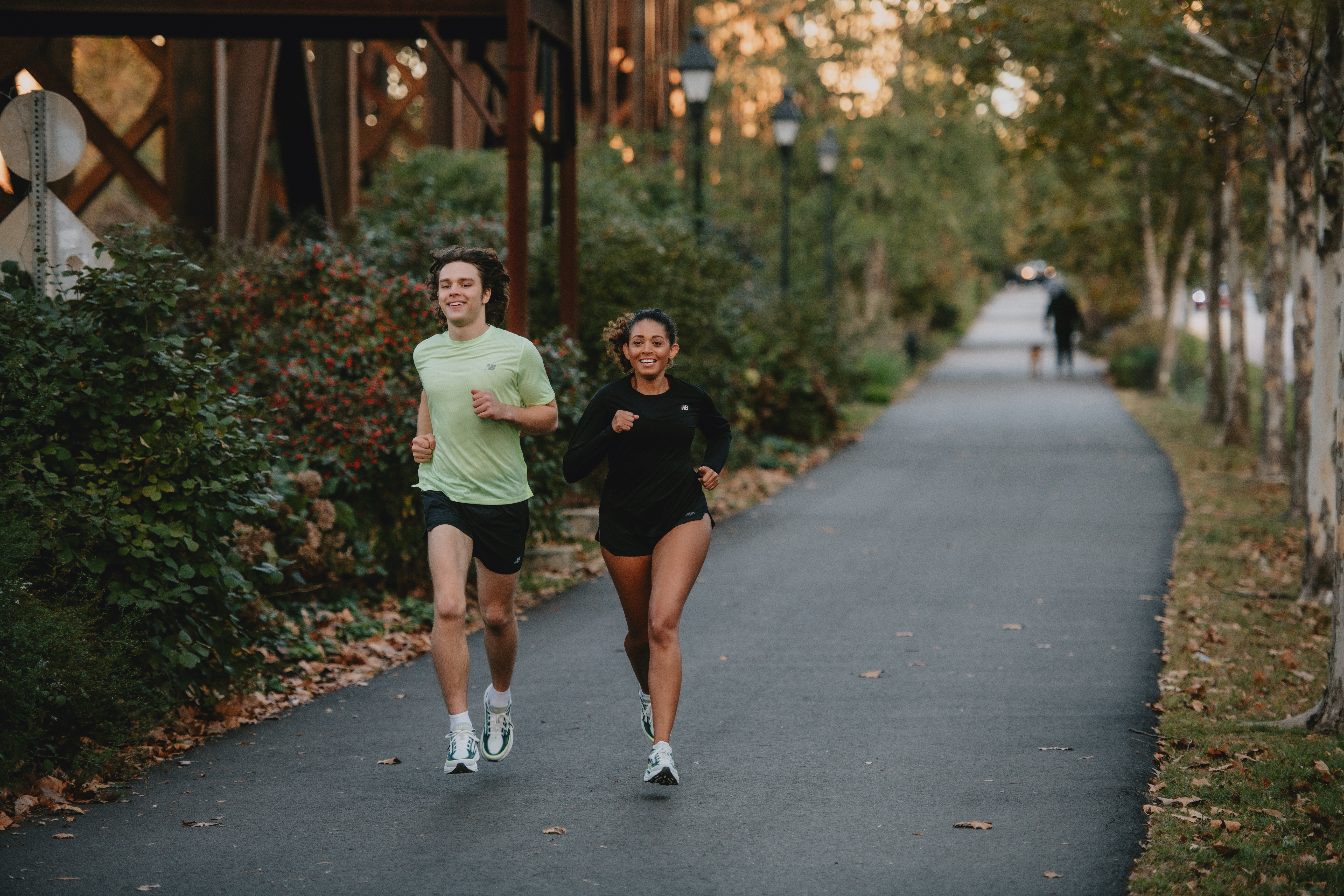 Two people smiling as they run together along a paved path