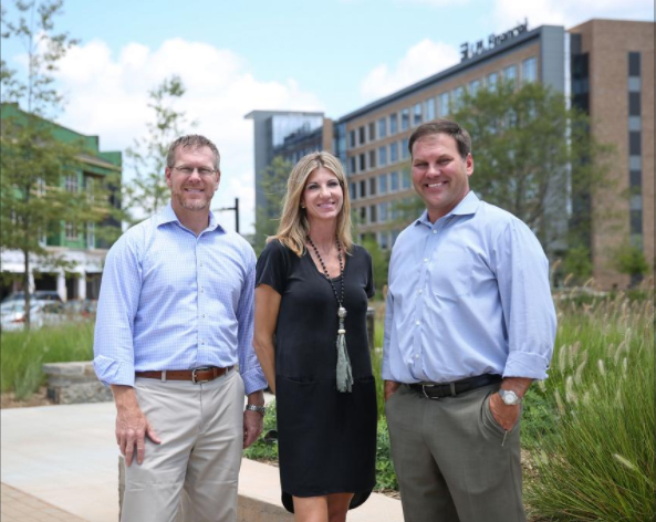 Dan Mummey and Kerri Robusto, both of Clear Springs, stand in Kingsley Town Center with Springs family member Dehler Hart, at right (Photo by Melissa Key, Charlotte Business Journal) 