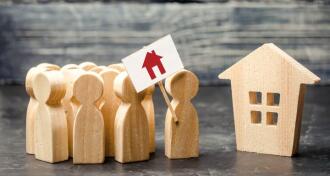 A crowd of people with a poster standing near the house