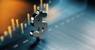 American dollar symbol standing on wood surface in front of a graph