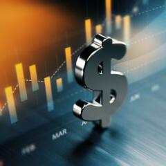 American dollar symbol standing on wood surface in front of a graph