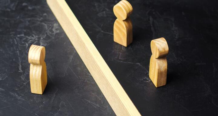 a wooden barrier between three wooden people