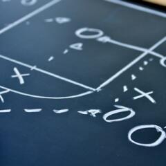 Blackboard with a basketball play written out using x's and o's and arrows