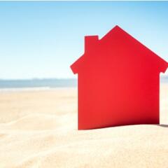 Red house cutout sticking out of sand on the beach