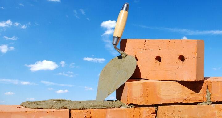 Rows of bricks and a trowel for bricklaying with a blue sky in the distance