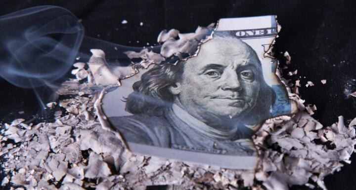 A one hundred dollar bill that has been burned around the edges 
