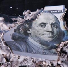 A one hundred dollar bill that has been burned around the edges 