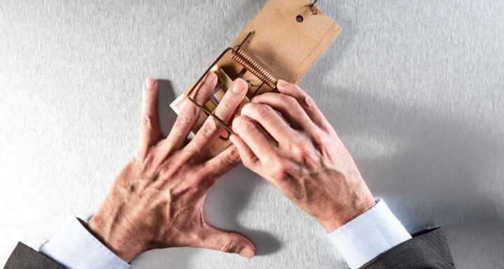 Businessman hand stuck in mouse trap