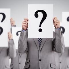 Businessmen holding signs with question marks over faces