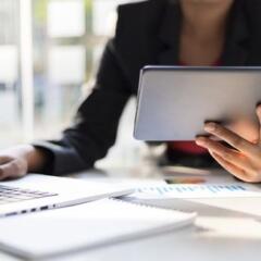 Business man holding tablet working on laptop and analyzing busines