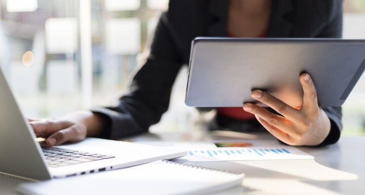 Business man holding tablet working on laptop and analyzing busines