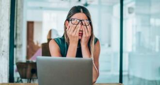 Business woman holding her face in her hands in despair