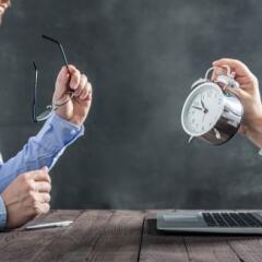Businessman looking at laptop with clock coming out with clock