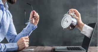 Businessman looking at laptop with clock coming out with clock