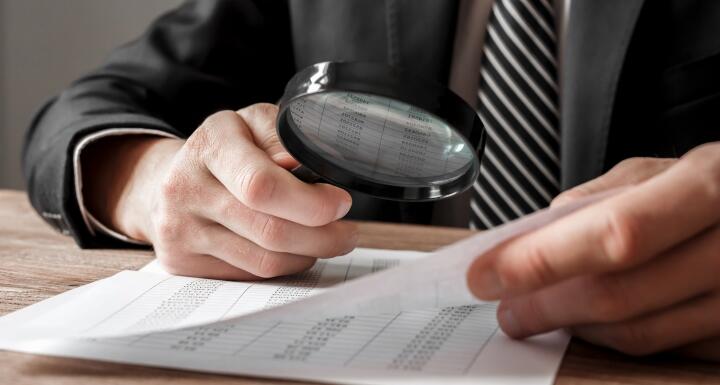 Man with Magnifying glass looking over contract