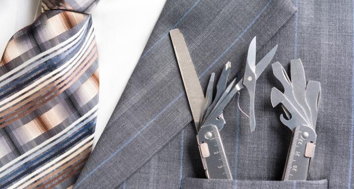Gray pinstripe suit pocket with a multi-purpose tool sticking out of the pocket