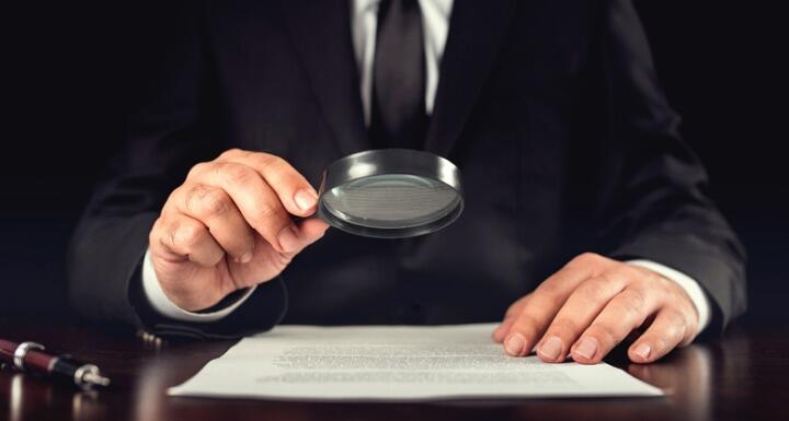 Businessman reading contract with magnifying glass