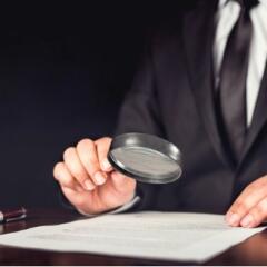 Businessman holding magnifying glass over document