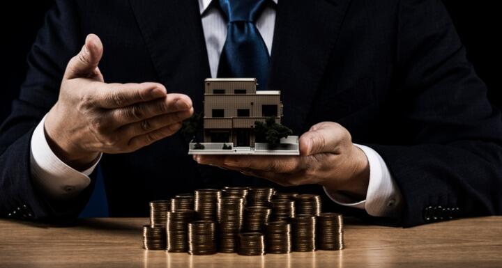 Businessman holding model building over stacks of coins