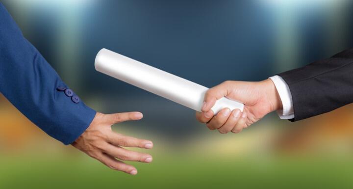 Close up shot of a businessman passing a silver baton to another businessman