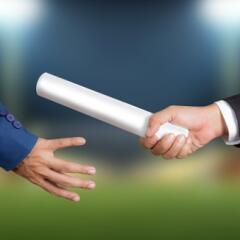 Close up shot of a businessman passing a silver baton to another businessman