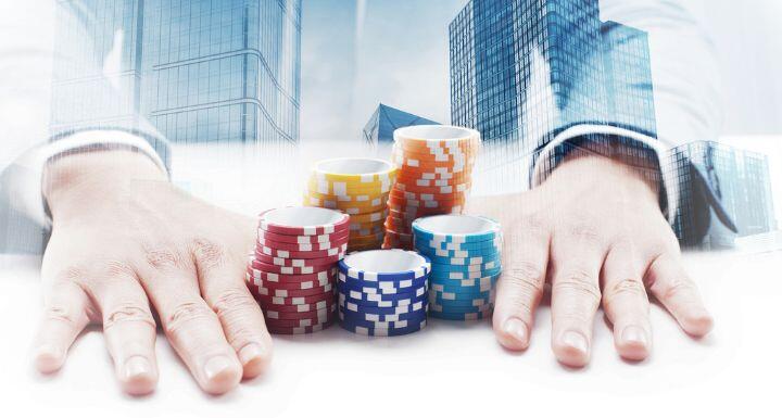 Businessman sitting by the desk pushing gambling chips with double exposure cityscape