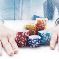 Businessman sitting by the desk pushing gambling chips with double exposure cityscape