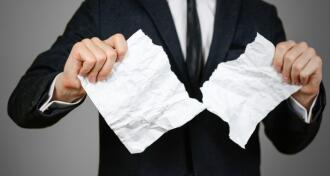 A man in a suit tearing up a paper meant to show he is contesting a will