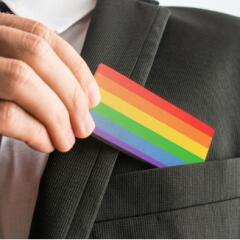 A man in a suit putting a rainbow business card in the outside chest pocket