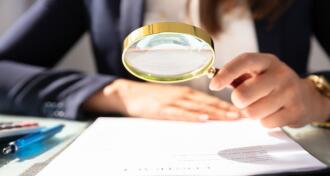 Businesswoman looking at contract with magnifying glass