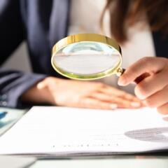 Businesswoman looking at contract with magnifying glass