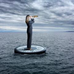 Business Woman Stands on Compass looking through spyglass in stormy Sea