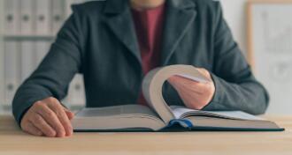 Businesswoman reading book at office desk