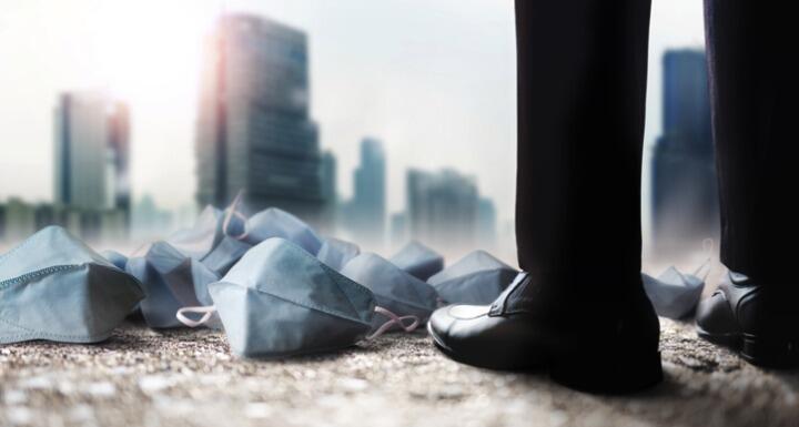 Many medical masks on the ground at business man's feet