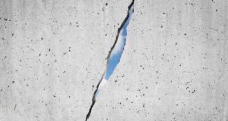 CRACKED CONCRETE WALL WITH SUNLIGHT SHINING THROUGH