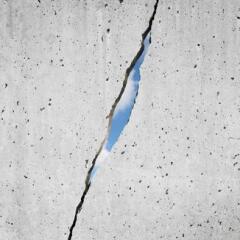 CRACKED CONCRETE WALL WITH SUNLIGHT SHINING THROUGH