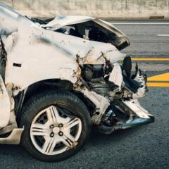 the front end of a white sedan with crash damage