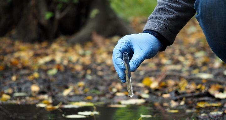Gloved hand collecting water samples
