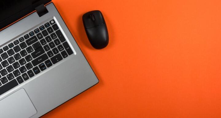 Close up of laptop and mouse on orange background