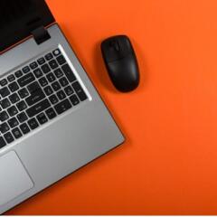Close up of laptop and mouse on orange background