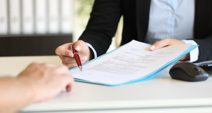 Close up of an executive hands holding a pen and indicating where to sign