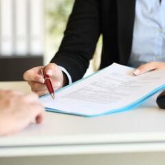 close up of an executive hands holidng a pen and indicating where to sign