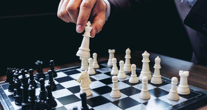 Close up of hands confident businessman colleagues playing chess game