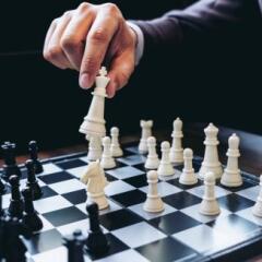 Close up of hands confident businessman colleagues playing chess game